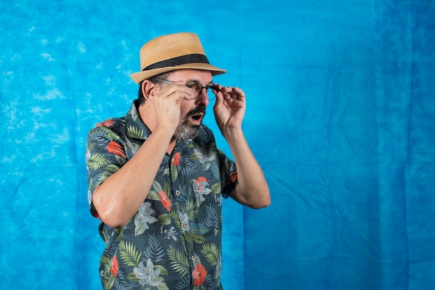 Als Tourist verkleideter Mensch mit bedrucktem Hemd und erstauntem Gesicht, der seine Brille abnimmt