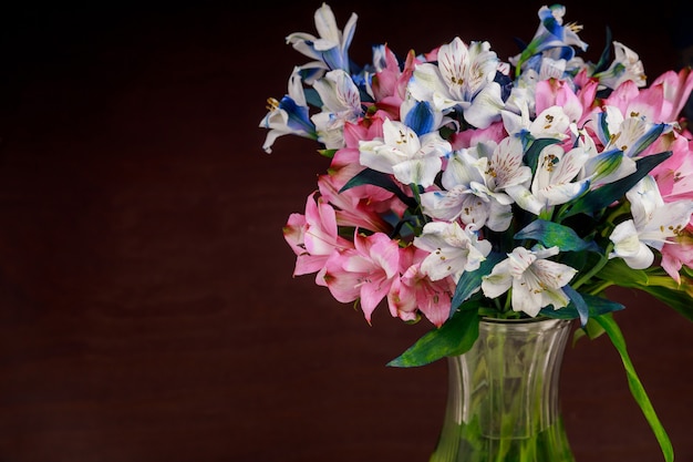 Alstroemeria blüht in Glasvase auf dunkler Oberfläche. Muttertag.