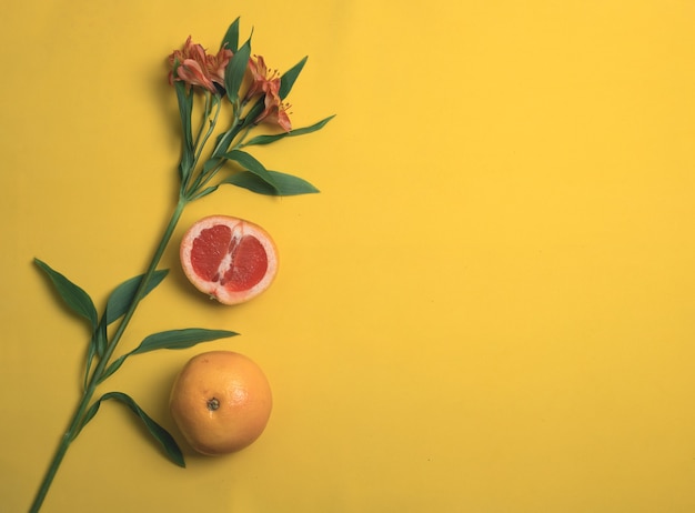 Alstroemeria e toranja em um fundo amarelo. vista do topo