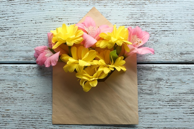 Foto alstroemeria rosa e crisântemo amarelo em envelope em fundo de madeira