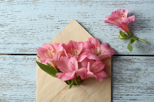 Alstroemeria rosa en sobre sobre fondo de madera