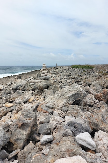 Foto una alta torre de piedras planas se encuentra en la orilla del mar en tiempo nublado