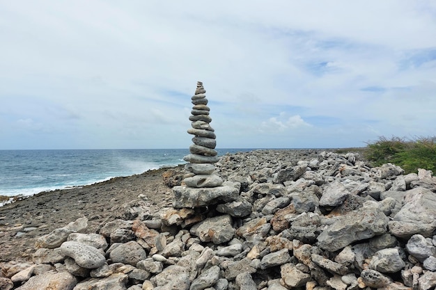 Una alta torre de piedras planas se encuentra en la orilla del mar en tiempo nublado