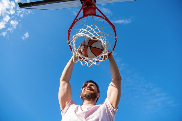 Alta visão do jogador de basquete joga a bola no aro ao ar livre, motivação