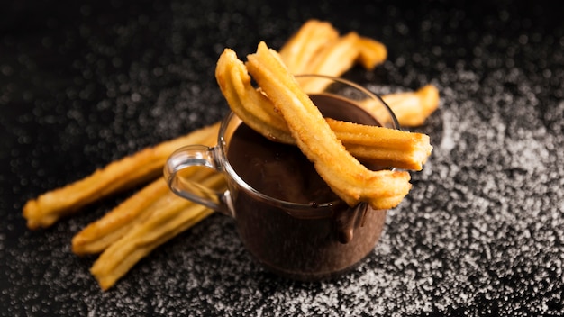 Alta vista churros y taza de chocolate derretido