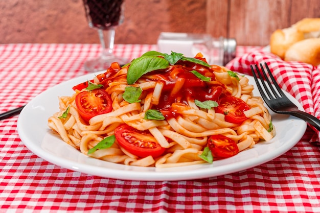 Alta vista de pasta de espagueti con una deliciosa salsa de tomate casera con hojas de albahaca casera