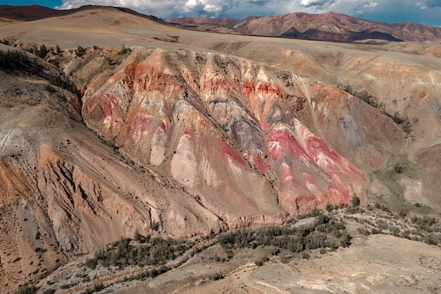 Altas colinas coloridas con muchos árboles verdes entre las llanuras montañosas bajo el cielo con algunas nubes.