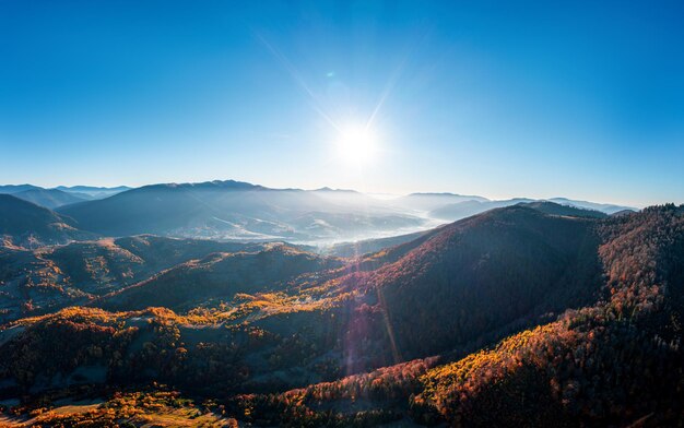 Altas cumbres montañosas con bosques amarillentos bajo un sol brillante