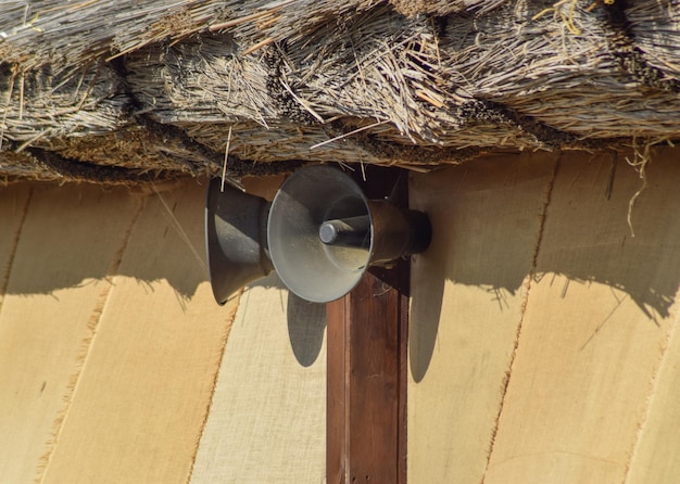 Altavoces de cuerno antiguos en una pared bajo un techo de paja