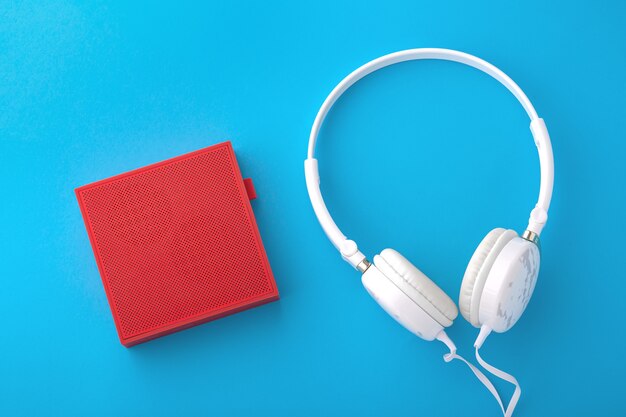 Altavoz inalámbrico rojo y auriculares con cable blancos