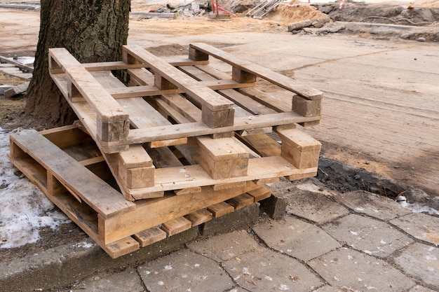 Alte abgenutzte Holzpaletten auf einer Baustelle in der Stadt Reparatur der Stadtstraße und des Bürgersteigs