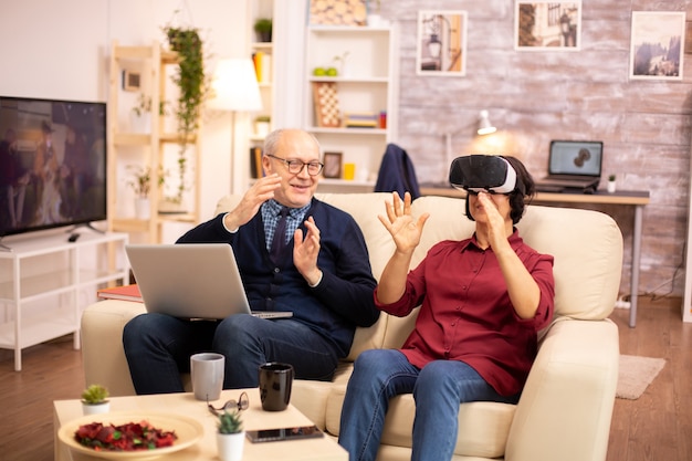 Alte ältere Rentnerin in ihren 60ern erlebt zum ersten Mal virtuelle Realität in ihrer gemütlichen Wohnung