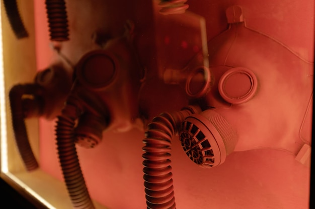 Alte Antigas-Atemschutzgeräte, die bei Rotlicht im Studio ausgestellt sind