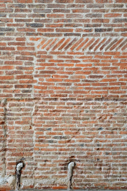 Alte Backsteinmauer und Rohr auf konkretem Beschaffenheitshintergrund für verzieren