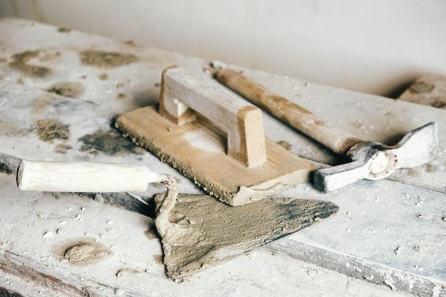 Alte Bauwerkzeuge für Putz auf Vintage-Holzbank Kellen und andere Maurerwerkzeuge