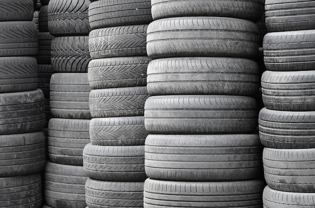 Alte benutzte Reifen gestapelt mit hohen Stapel in der Sekundärautoteil-Werkstattgarage