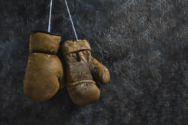 Foto alte braune boxhandschuhe, die an der wand hängen.