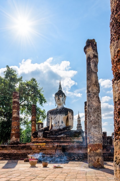 Alte Buddha-Statue, die unter den Ruinen unter der hellen Sonne des Wat Maha That-Tempels im Sukhothai Historical Park sitzt, ist eine alte Stadt und berühmte Touristenattraktion der Provinz Sukhothai, Thailand