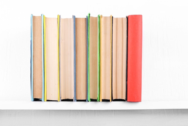 Alte Bücher auf Bücherregal auf weißem Wandhintergrund