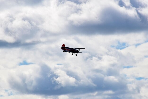 Alte Doppeldecker mit Propeller fliegen in den blauen bewölkten Himmel