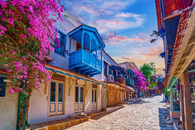 Alte farbige Straßenansicht Weiße Häuser mit hölzernen blauen Balkonen und rosa Blumen in der Stadt Kas Türkei