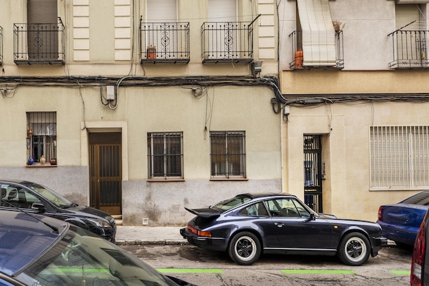 Alte Fassaden in einem bescheidenen Viertel von Madrid mit einem auf der Straße geparkten Oldtimer-Sportwagen