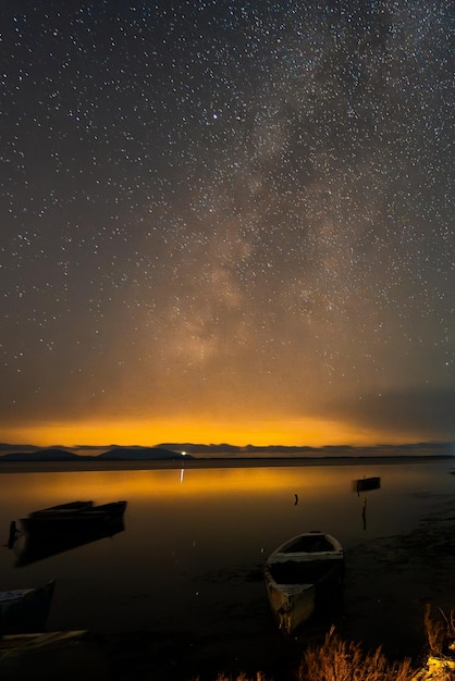 Foto alte fischerschiffe in der albanischen lagune in der nacht sternenhimmel mit der milchstraße