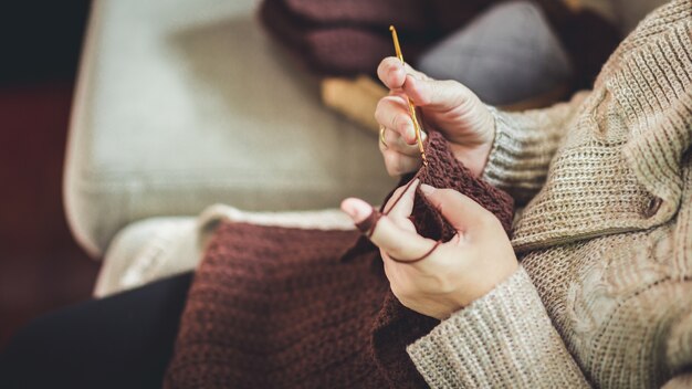 Alte Frau, die einen braunen Schal strickt