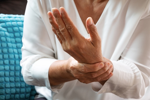 Alte Frau, die unter Handgelenkhandschmerz, Gesundheitsproblemkonzept leidet