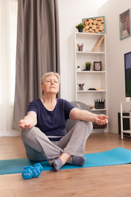 Alte Frau, die zu Hause Yoga für ein gesundes Leben praktiziert.