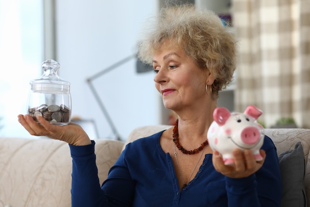 Foto alte frau halten sparschwein mit ersparnissen in ihren händen.