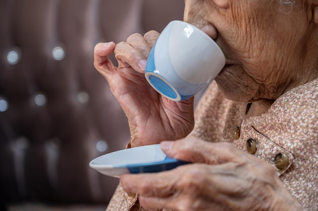 Alte Frau trinkt Kaffee im Wohnzimmer