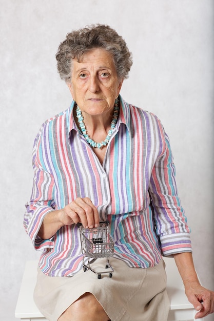 Foto alte frau zwischen 70 und 80 jahren mit einem mini-einkaufswagen.