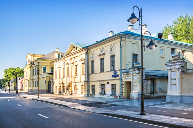 Alte Gebäude von gelben Villen auf Pyatnitskaya Straße in Moskau und Laternen an einem sonnigen Sommermorgen. Inschrift: Pyatnitskaya Straße