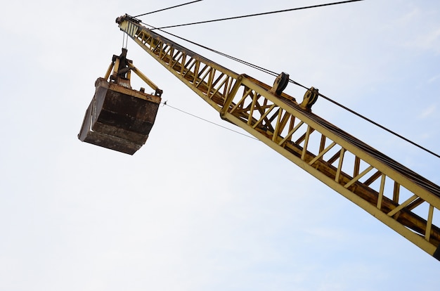 Alte gelbe mechanische Muschel greifen auf Hintergrund des blauen Himmels