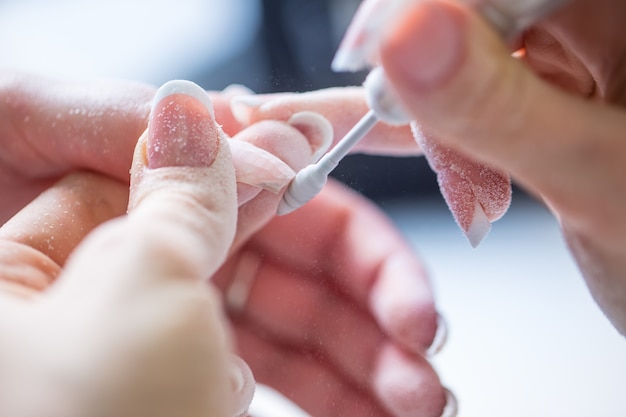 Alte Gelnägel mit einem Nagelschleifer im Nagelstudio reparieren