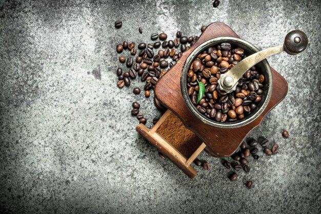 Alte Handmühle mit Kaffeebohnen. Auf einem rustikalen Hintergrund.