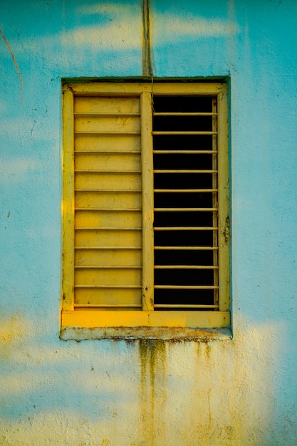 Alte Hauswand mit gelbem Holzfenster