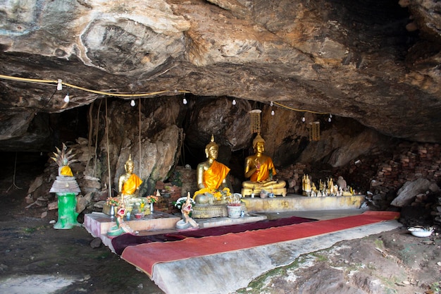 Alte heilige Buddha-Statue in einer antiken Geheimnishöhle für Thai-Leute, die reisen, besuchen, respektieren, beten, segnen, Glück wünschen des Wat Khao Phra Si Sanphet Chayaram-Tempels in der Stadt U Thong in Suphan Buri, Thailand