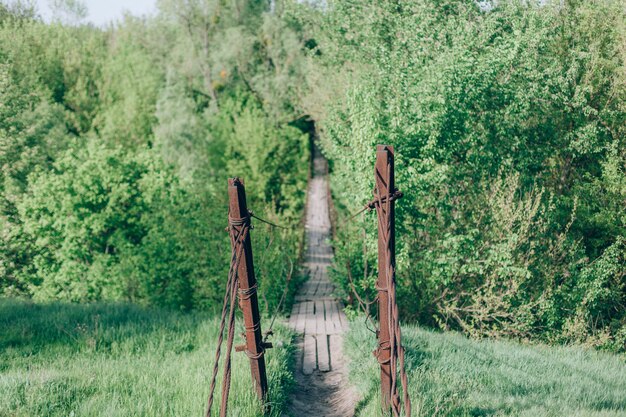 Foto alte hölzerne bridge.old hängende fußgängerbrücke über einen kleinen fluss hängen