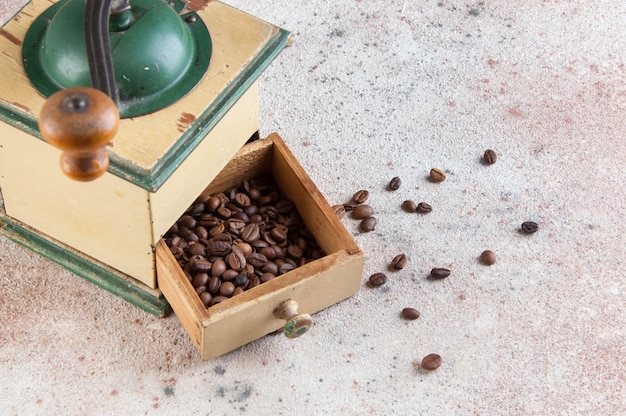 Alte hölzerne Kaffeemühle auf konkretem Hintergrund.