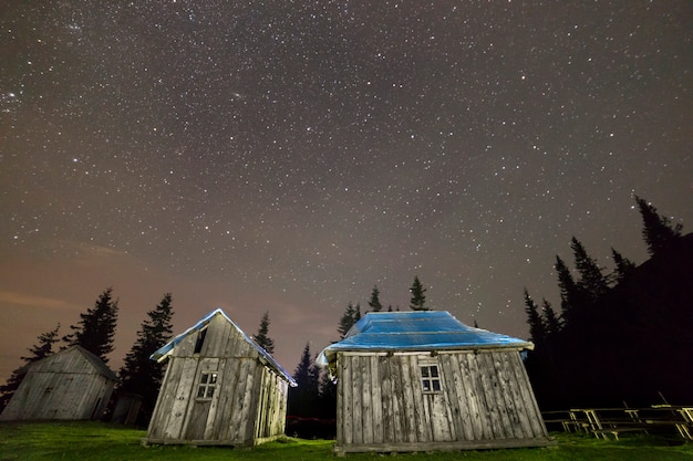 Alte hölzerne schäferhütten auf den bergen, die unter sternenklarem himmel sich klären.