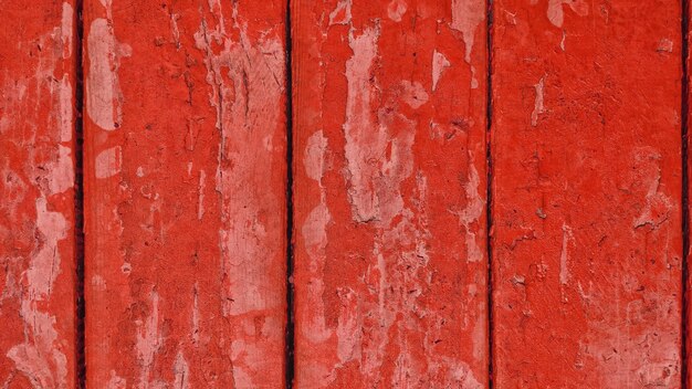 Alte Holzbretter mit roter abblätternder Farbe mit Rissen.