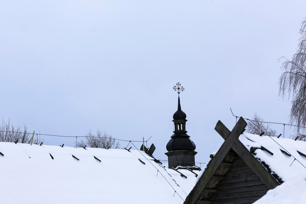 Alte Holzkirche aus Rundholz Kreuz auf der Kuppel Russische Winterlandschaft Schneebedeckte Bäume Verlassenes altes russisches Dorf mit Schnee bedeckt