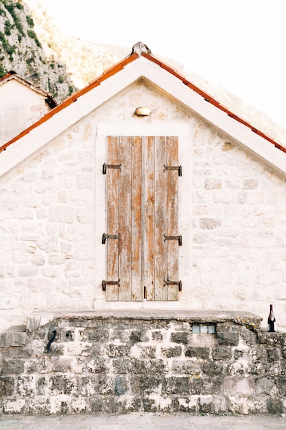 Alte Holztür zum Dachboden in einer weißen Wand mit einem orangefarbenen Dach