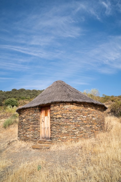 Alte Kabine oder Hütte mit runder Form und Schiefersteinwänden und einem Besen- und Strohdach