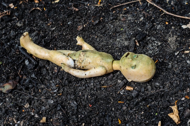 Alte kaputte Puppe auf dem Haufen der Asche