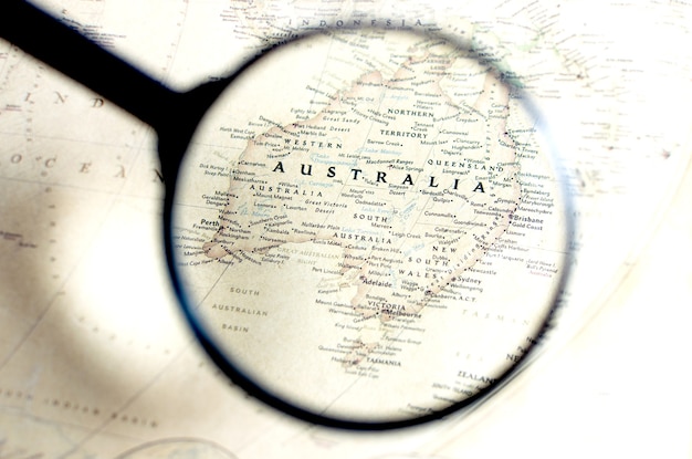 Alte Karte mit Territorium von Australien und dem Namen des Landes wird durch eine Lupe vergrößert.