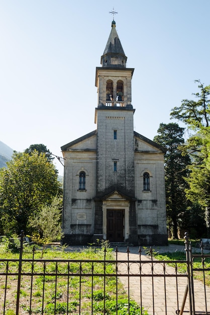 Alte Kirche mit Glockenturm inmitten grüner BäumeArchitektur und Antiquitäten