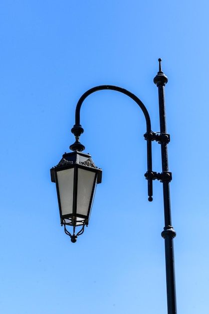 Alte Laterne auf einem Metallpfosten gegen blauen Himmel